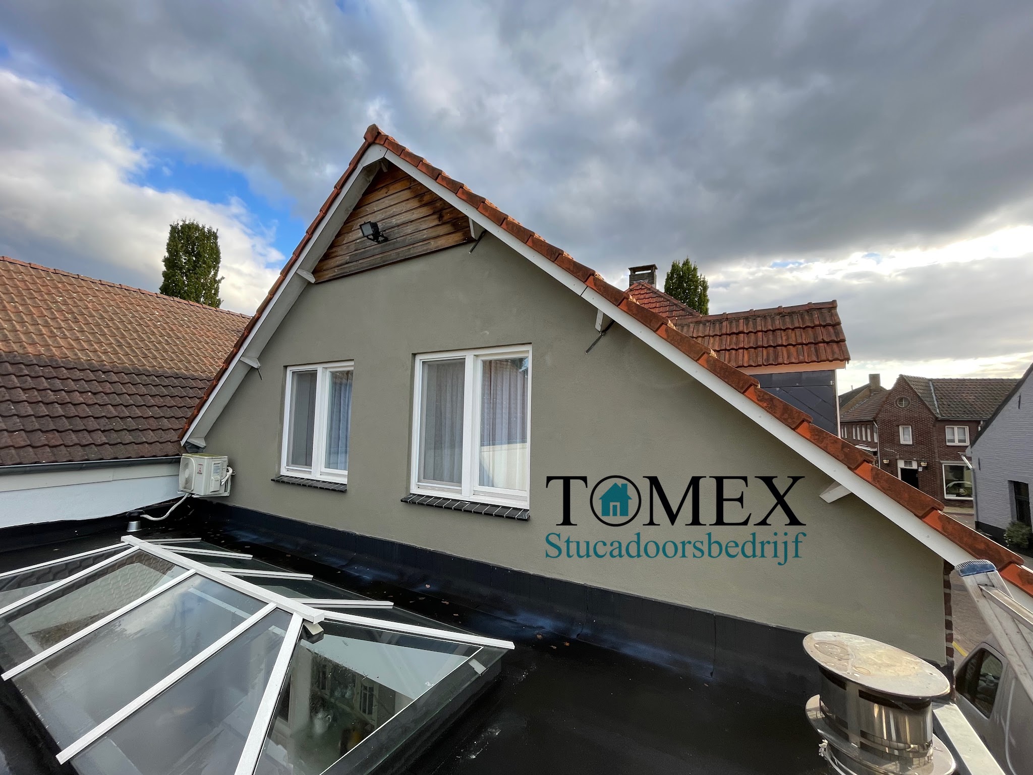 Gestucte gevel van een woning boven een glazen dak